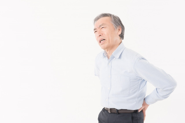 腰を抑えている男性の写真
