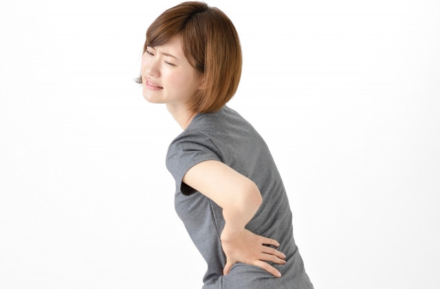 腰を抑える女性の写真